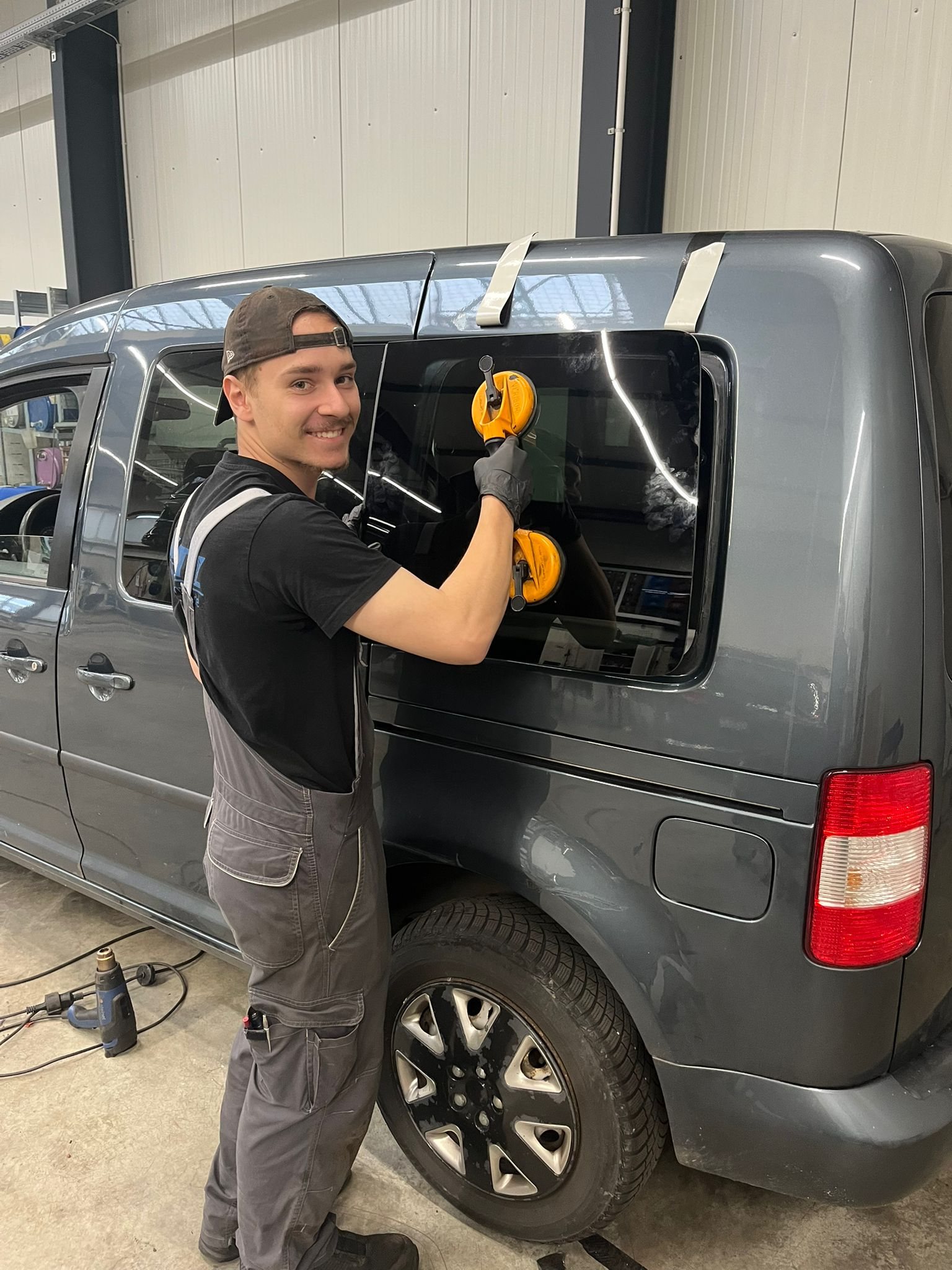 Junger Mitarbeiter beim Einbau einer Fahrzeugscheibe